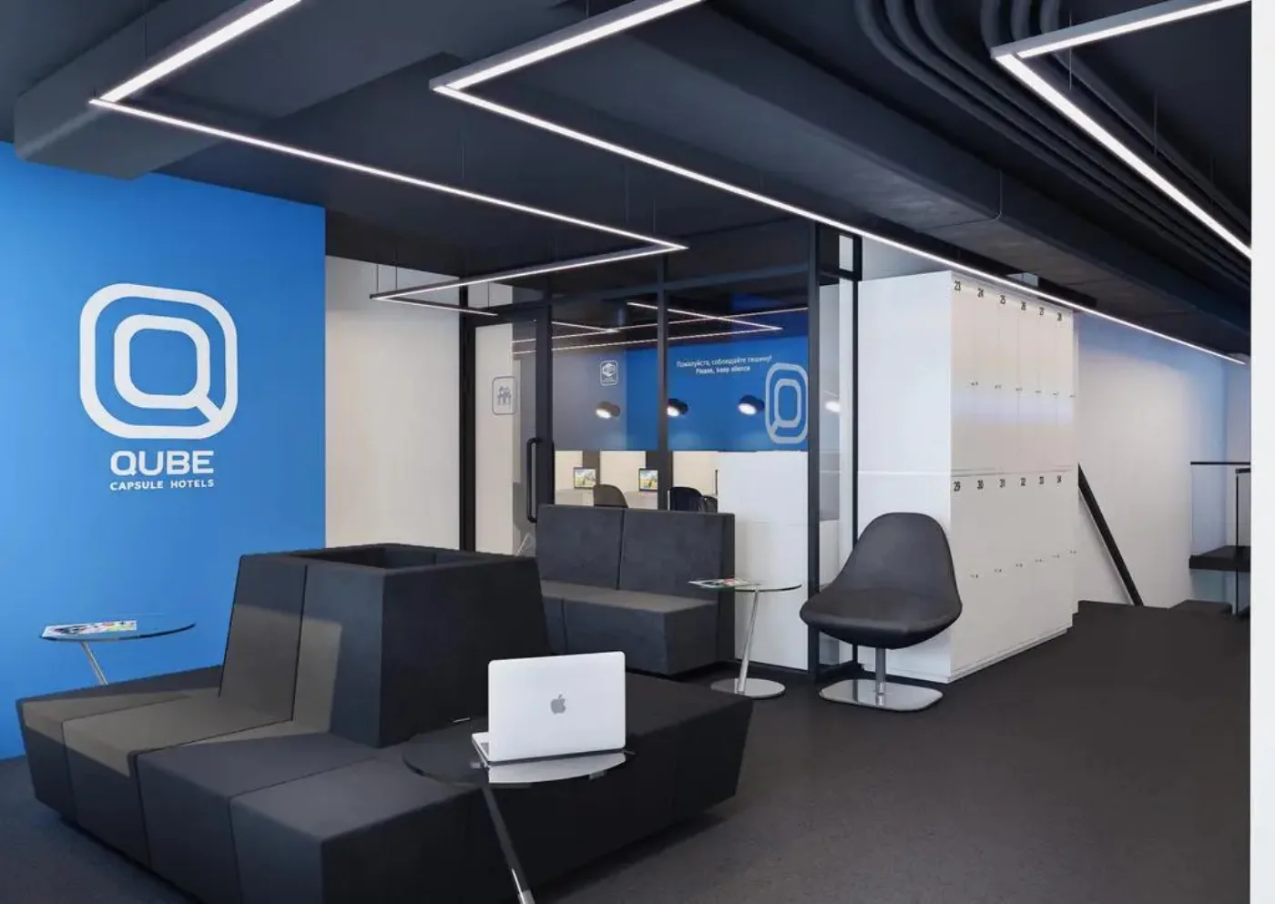 Лобби Qube Capsule Hotels с синей стеной логотипа, диванами и локерами