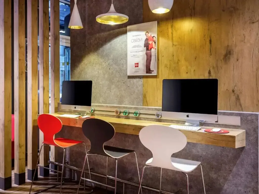 Рабочая зона лобби ibis с компьютерами и красным логотипом на постере