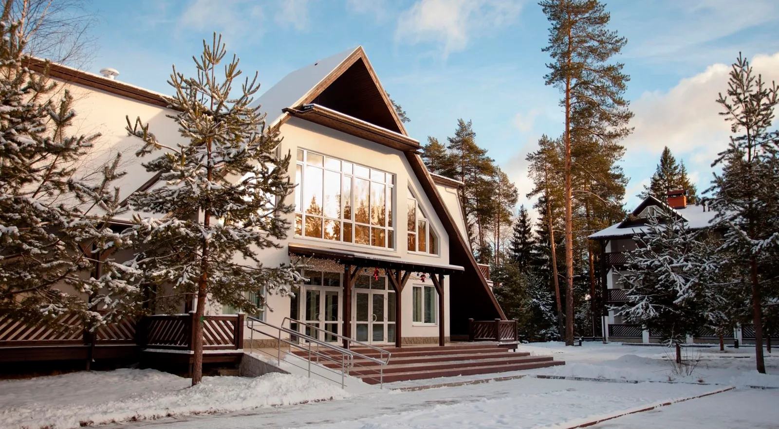 Зимний фасад Country Resort с A-образной крышей среди сосен